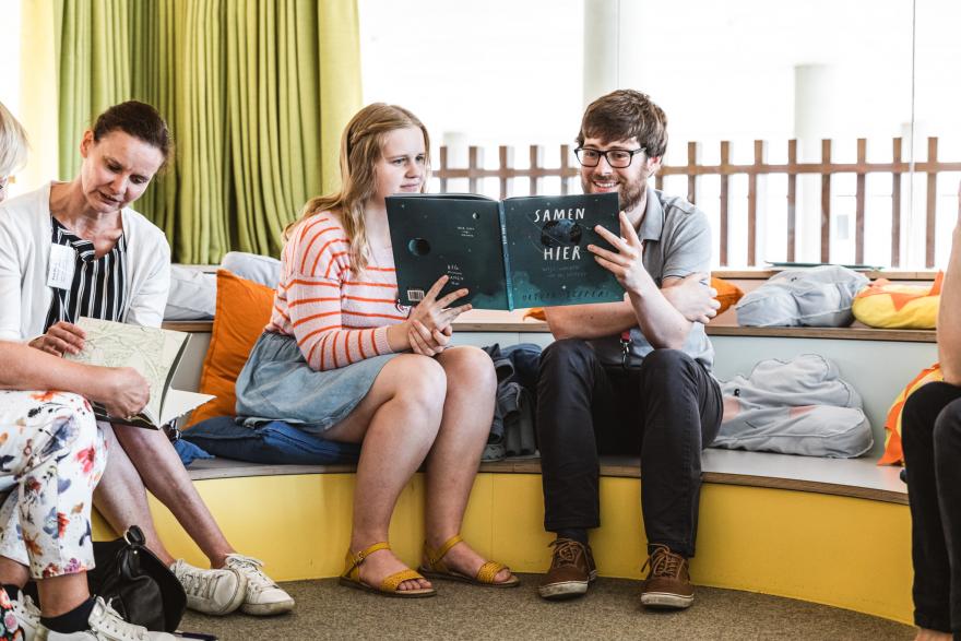 twee volwassenen lezen samen in een kinderboek