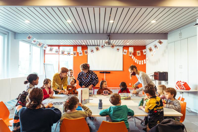 een groep kinderen zit rond een grote tafel iets te eten