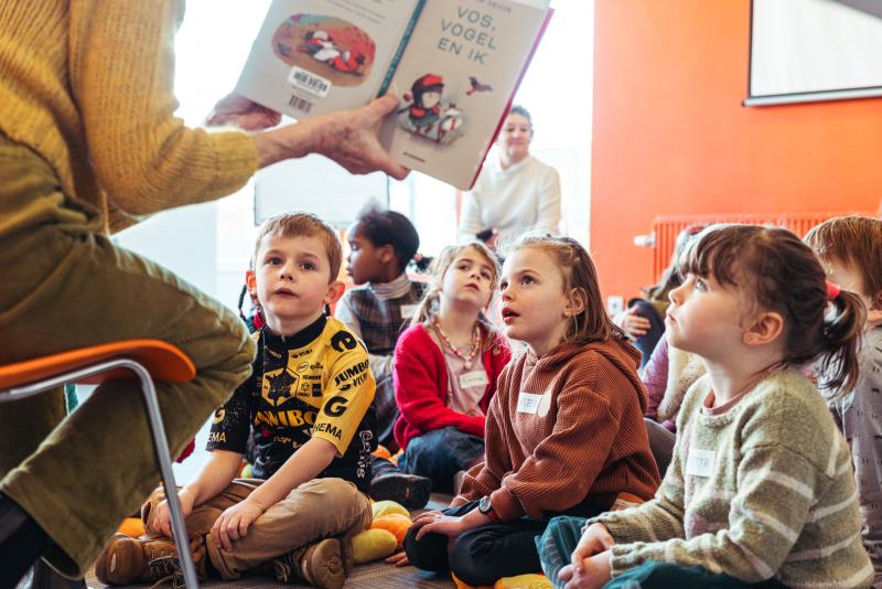 een groep kinderen luistert geboeid naar een verhaal