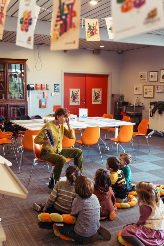 een begeleidster leest een Leesjury-boek voor aan een groep kinderen